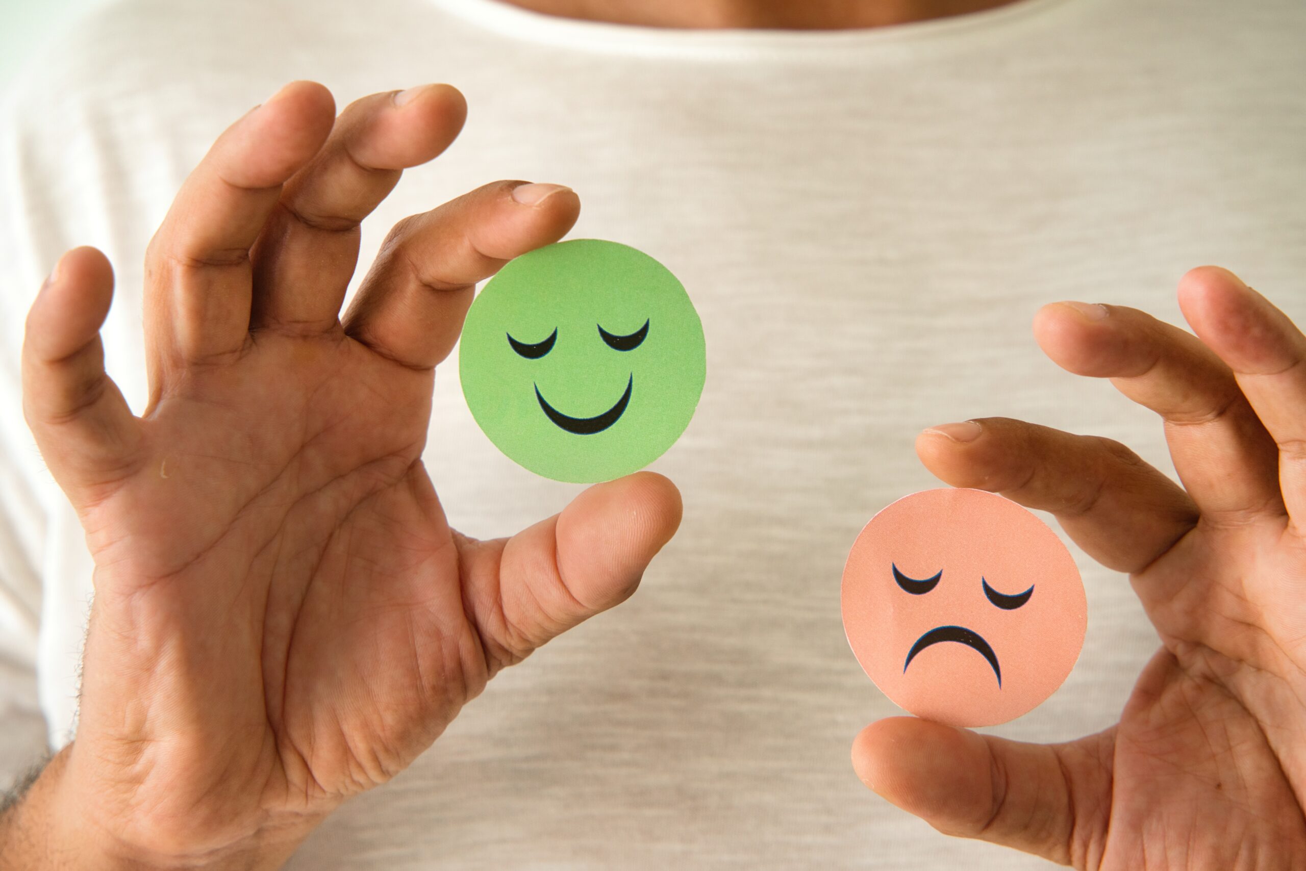 Man holding a positive green emoji and a red one. Smile, satisfaction, anger.