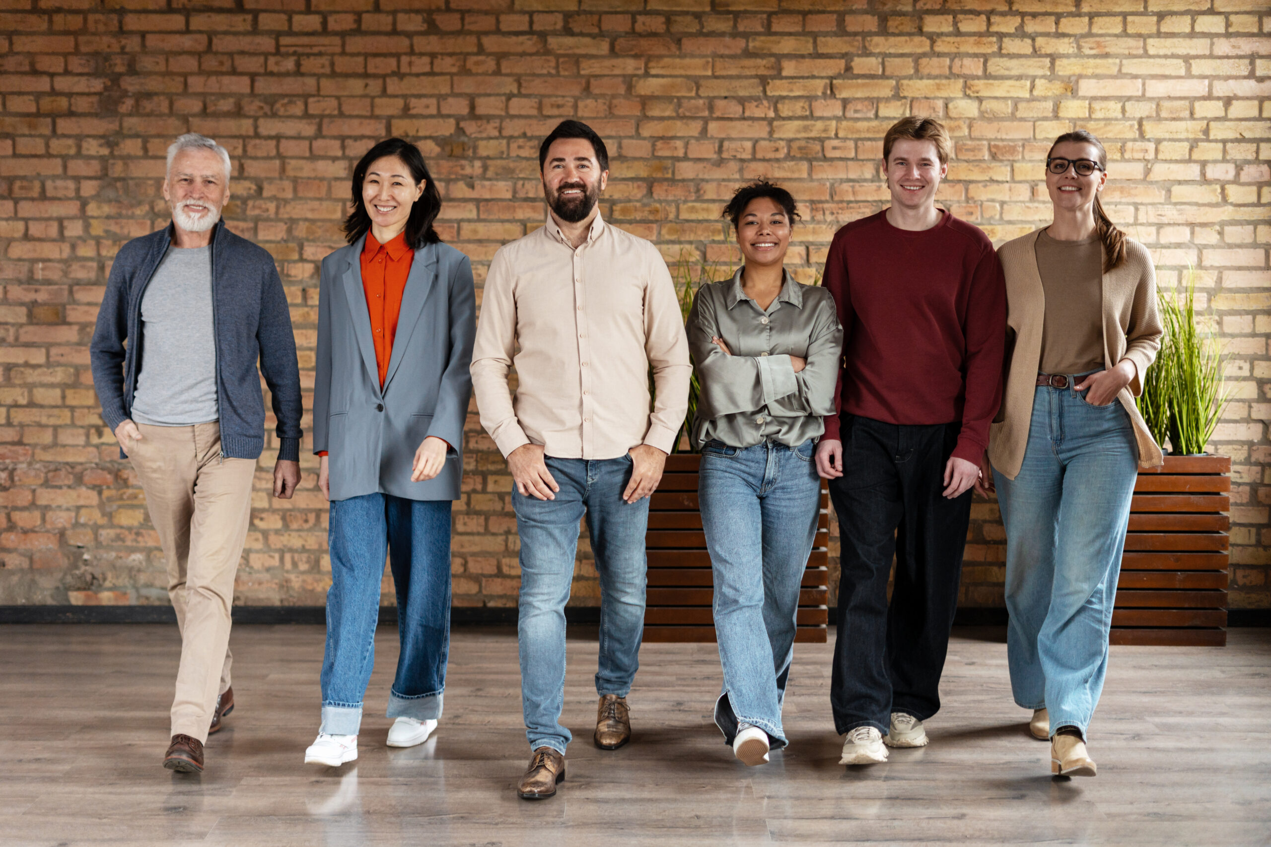 Diverse startup business team walking confidently through a modern office featuring a stylish brick wall, embodying collaboration and unity