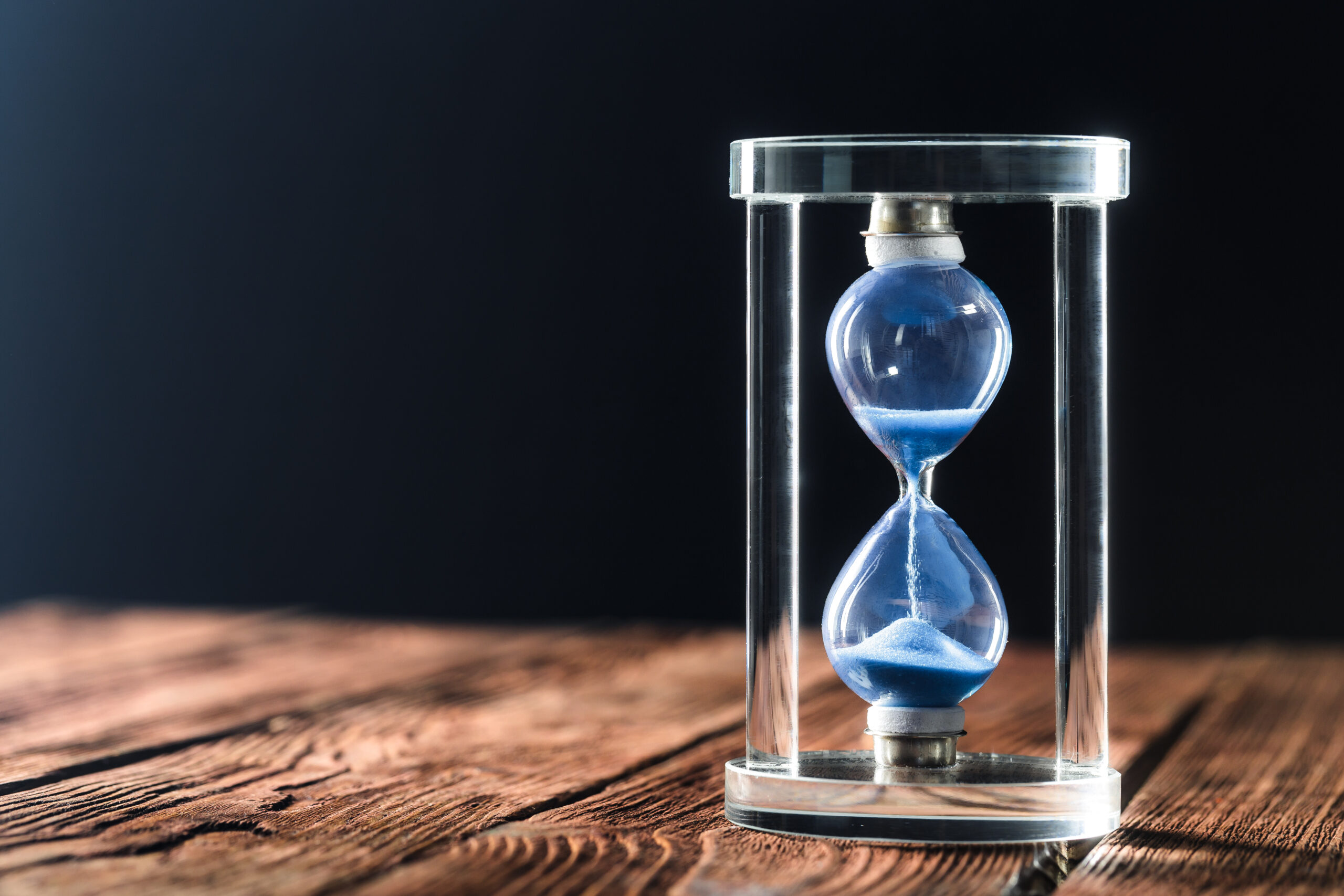 Modern hourglass on wooden background