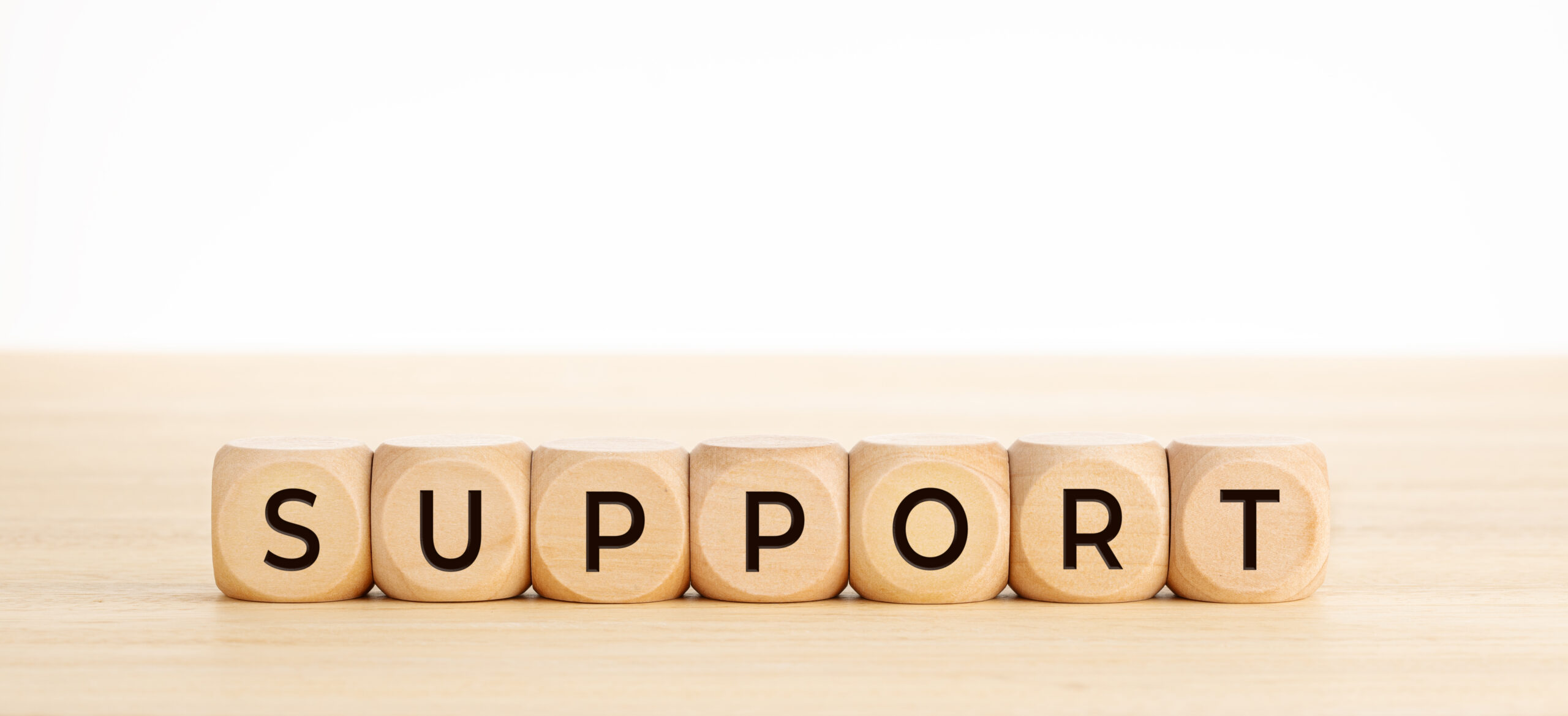 Support word on wooden blocks on wood table. Copy space. White background